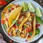 Three salsa chicken tacos with some sliced limes.