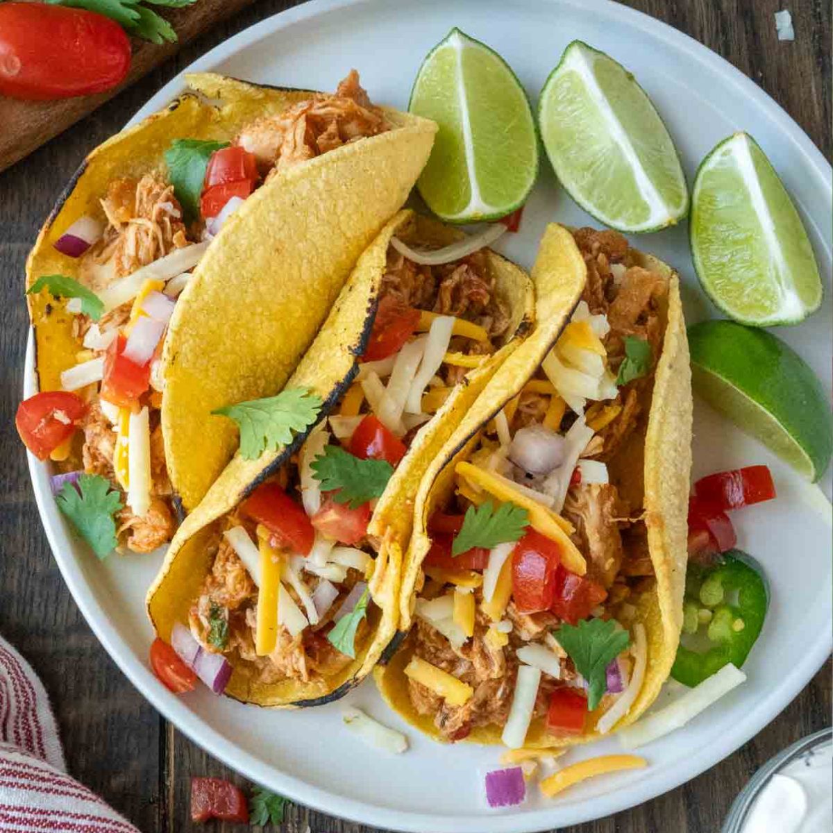 Three salsa chicken tacos with some sliced limes.