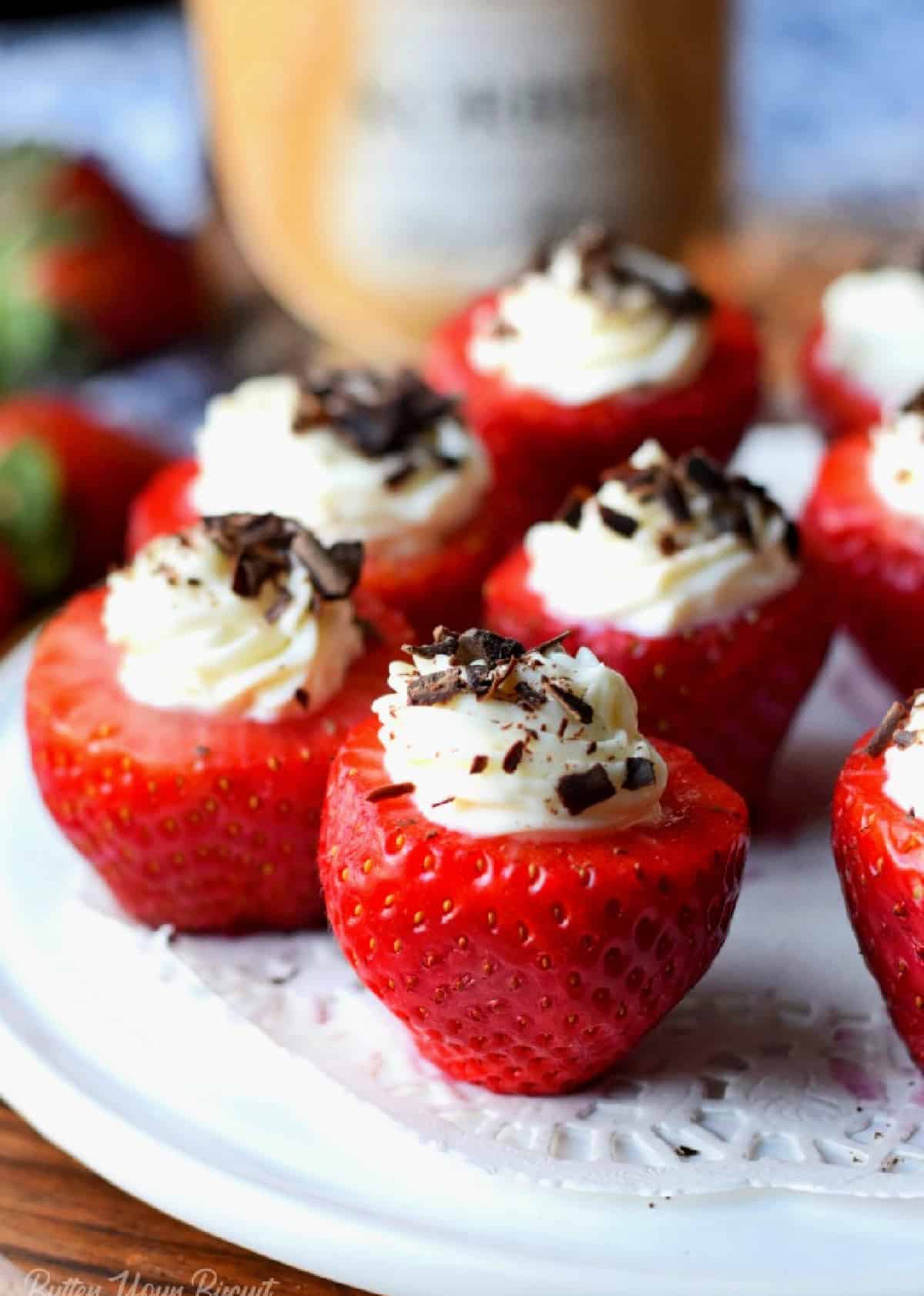 Several cheesecake stuffed strawberries on a white platter.