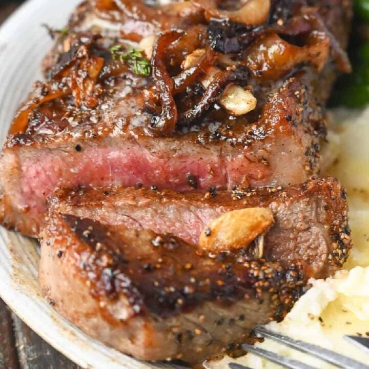 Garlic Rib Eye Steak with garlic is pan-seared to perfection with the perfect crust. Basted in butter, garlic, and fresh herbs, and topped with those sweet caramelized onions, and comes together in under 20 minutes.