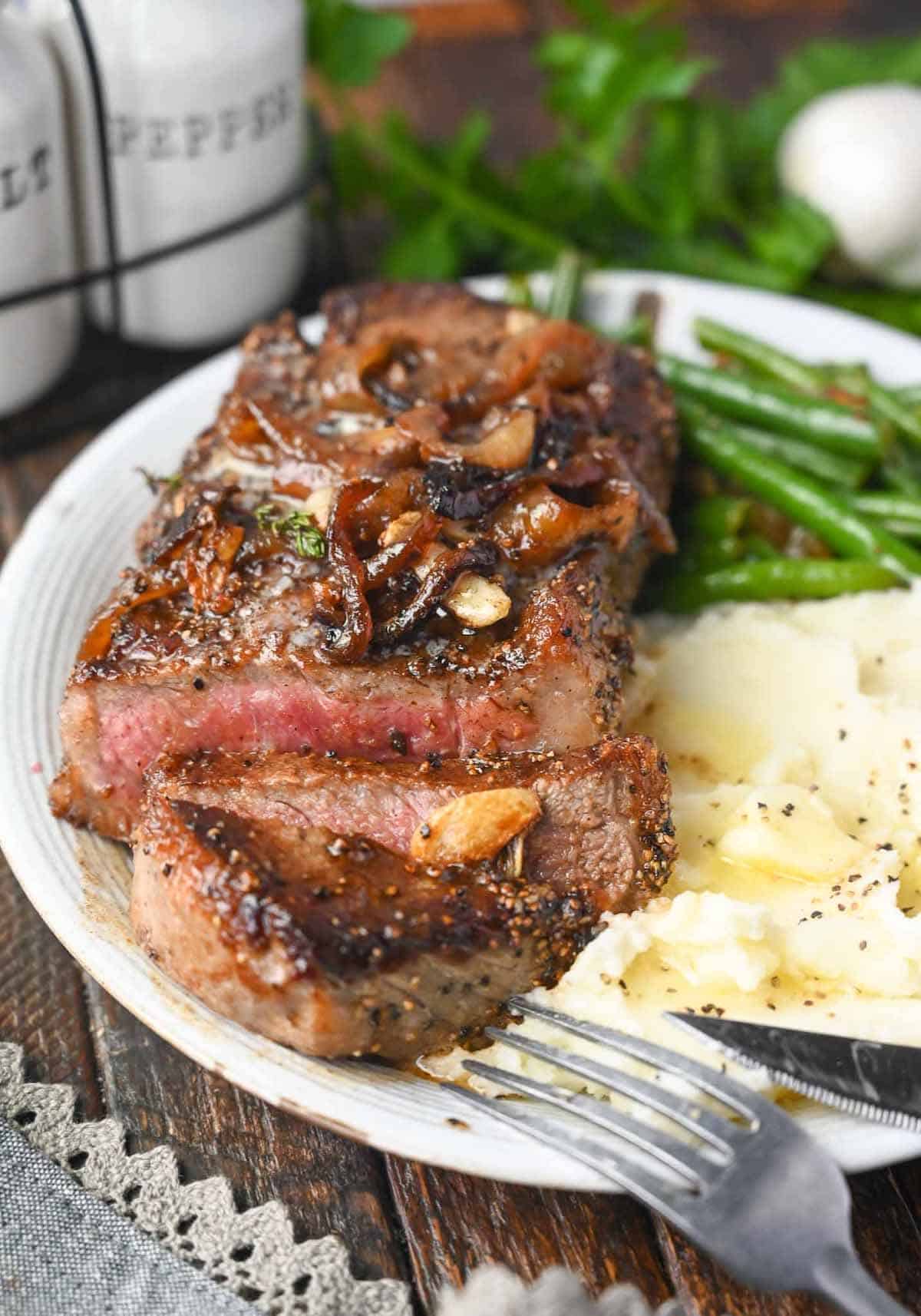 Garlic Rib Eye Steak with garlic is pan-seared to perfection with the perfect crust. Basted in butter, garlic, and fresh herbs, and topped with those sweet caramelized onions, and comes together in under 20 minutes.