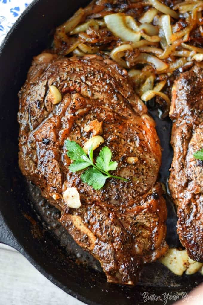 A skillet filled with rib-eye steak and onions.