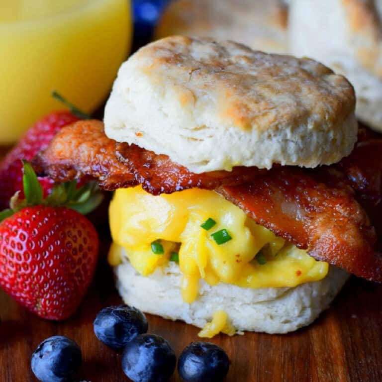 Bacon egg and cheese biscuit sandwich on a cutting board.
