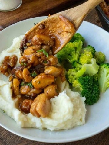 Honey butter garlic chicken on top of mashed potatoes with broccoli.