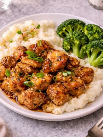 Honey butter garlic chicken on top of mashed potatoes with broccoli.