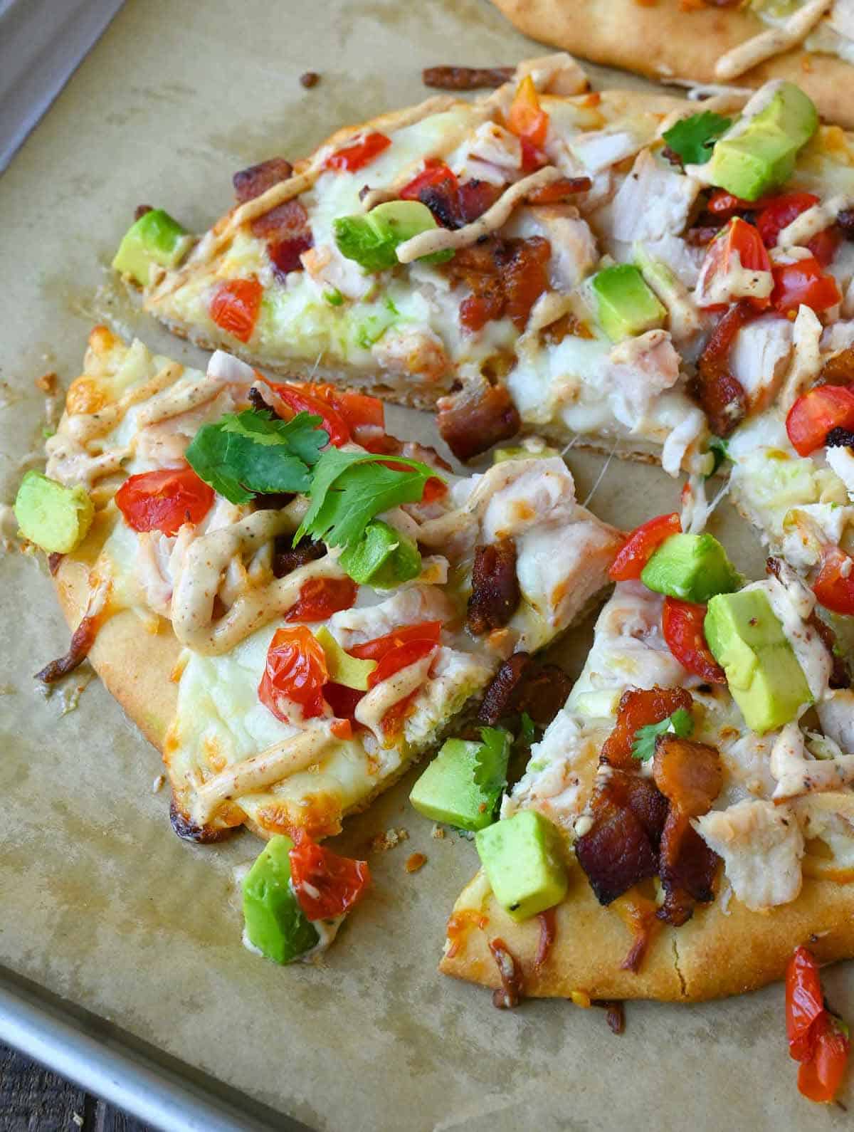 chicken club flatbread on a baking sheet that has been sliced.