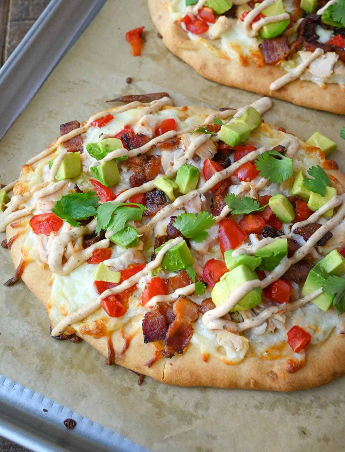 Chicken club flatbread on a baking sheet.