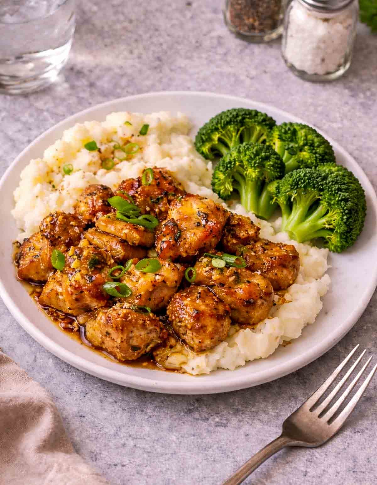 Honey butter garlic chicken on top of mashed potatoes with broccoli.