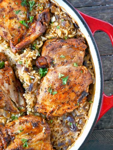 Paprika chicken thighs with rice in a red cast iron pan.