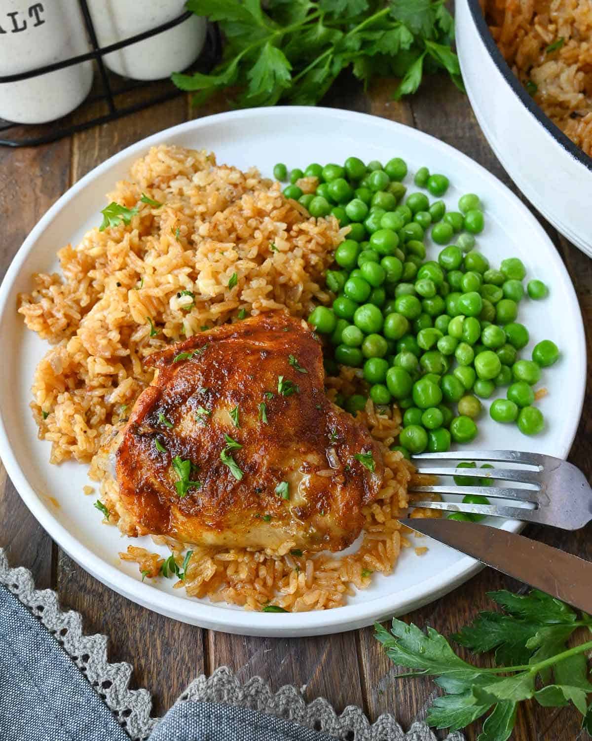 Paprika chicken and rice on a white plate with peas.