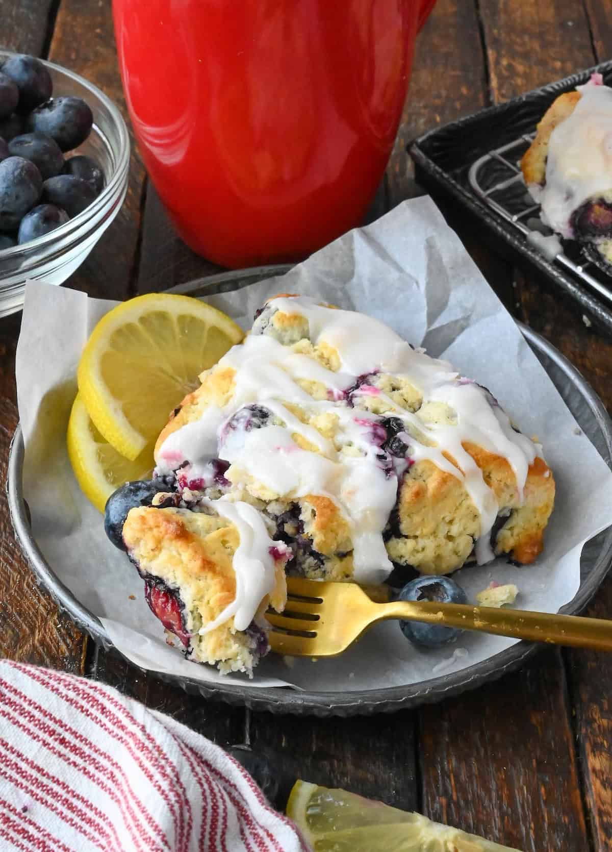 Blueberry scone on a plate with a fork.