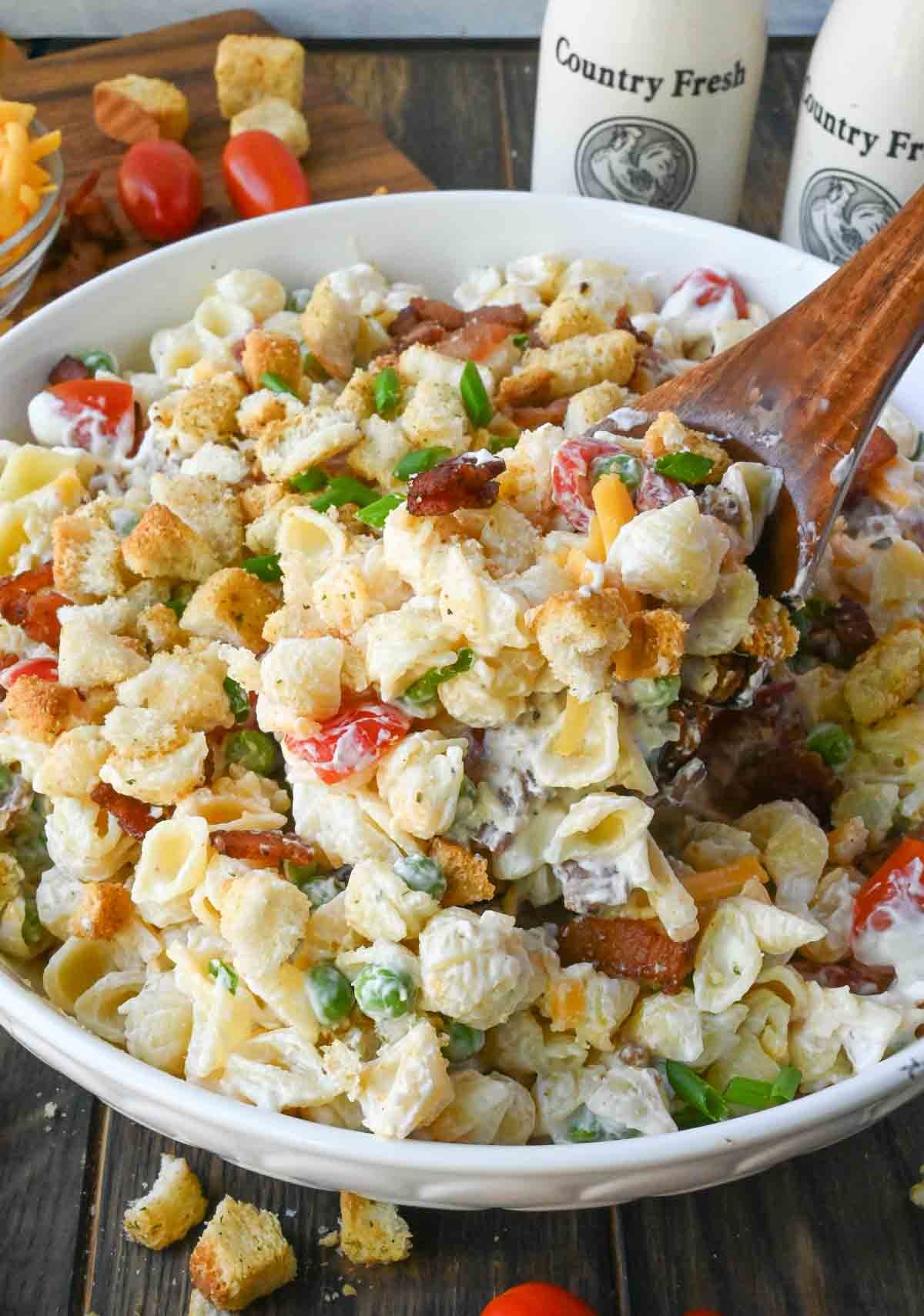 A wooden spoon scooping up some pasta salad.