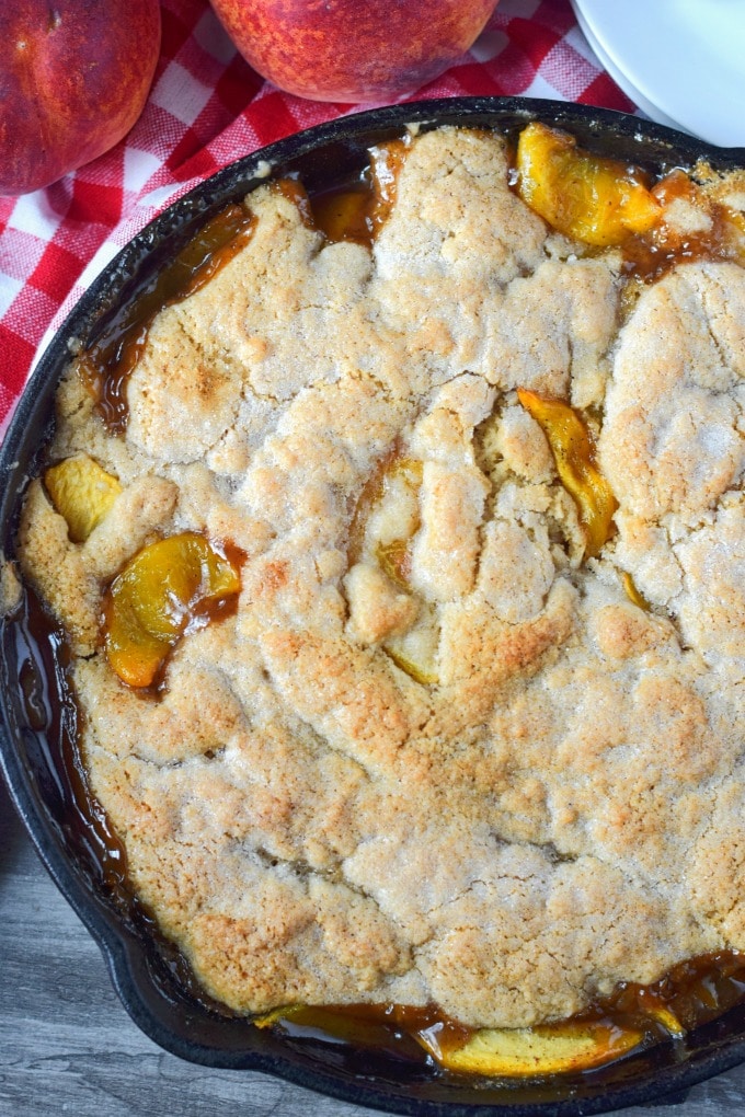 A close up photo of peach cobbler in a cast iron skillet.
