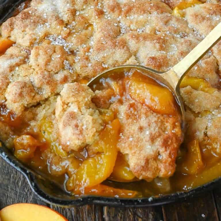 A serving spoon scooping out some peach cobbler.