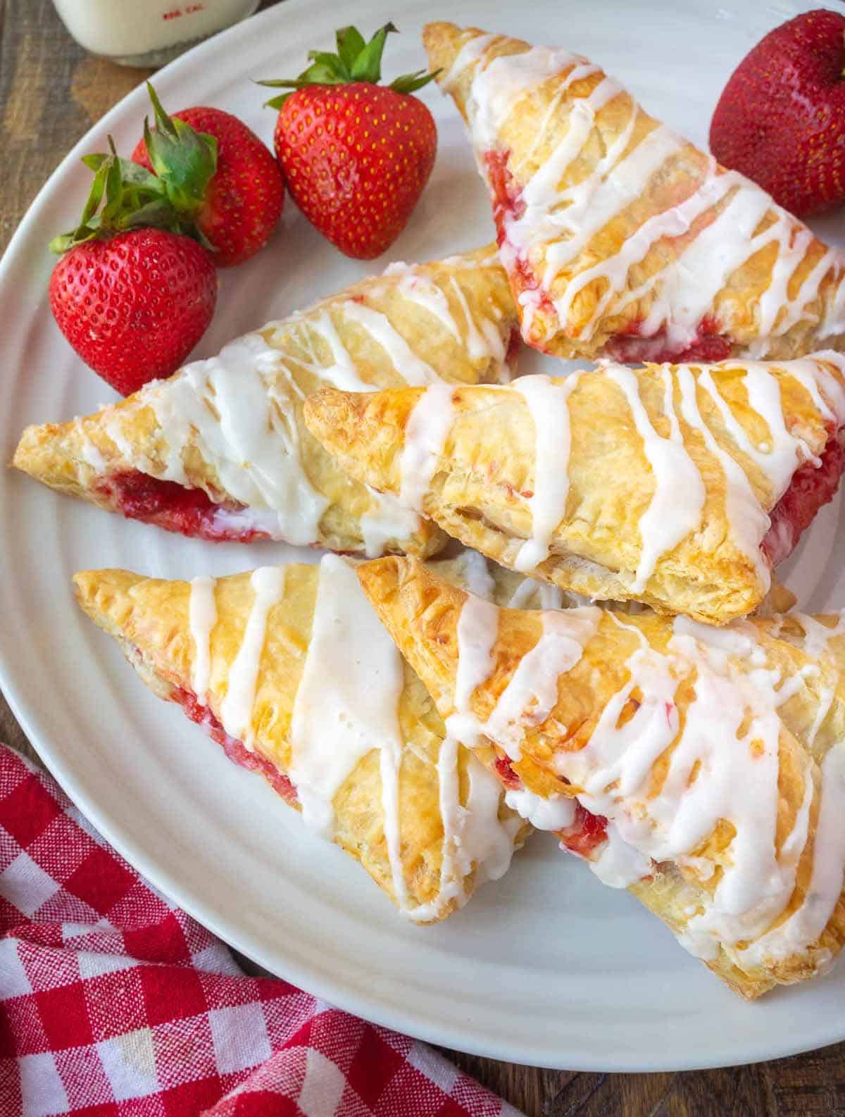 Strawberry turnovers on a platter with fresh strawberries.