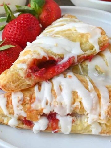 Two strawberry turnovers on a plate with a fork.