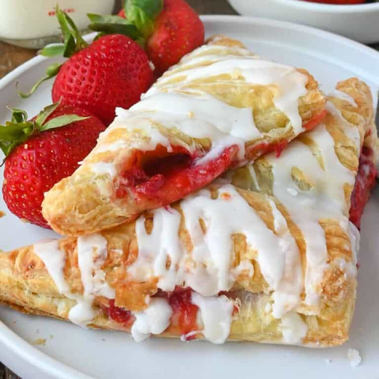 Two strawberry turnovers on a plate with a fork.