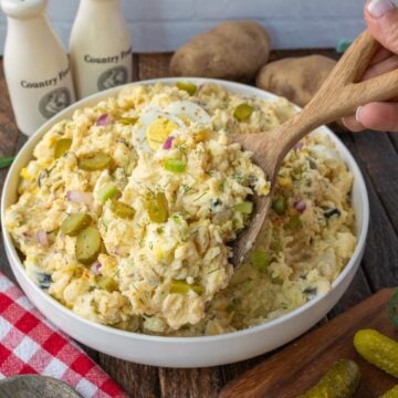 Potato salad with pickles in a white bowl.
