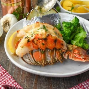 Lobster tail on a plate with butter dripped on top.