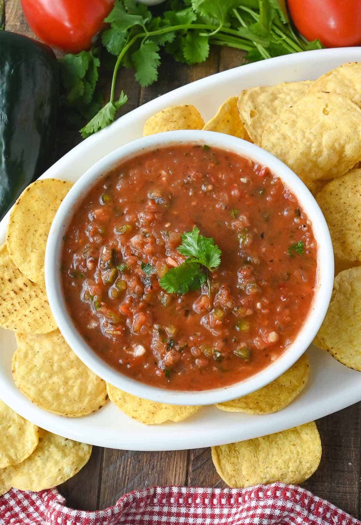Fire roasted salsa in a white bowl with tortilla chips on the side.