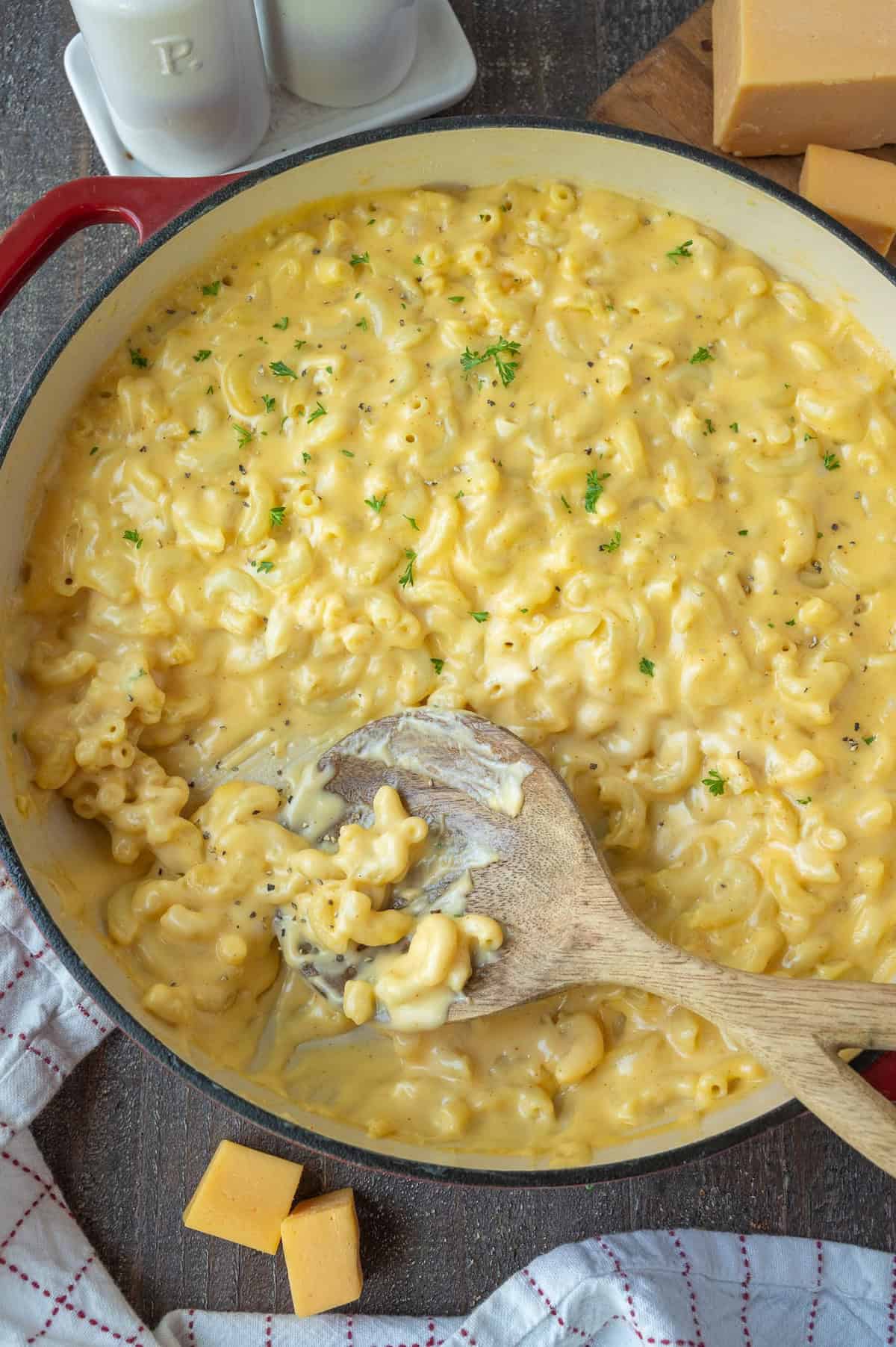 Creamy mac n cheese in a skillet with a wooden spoon.