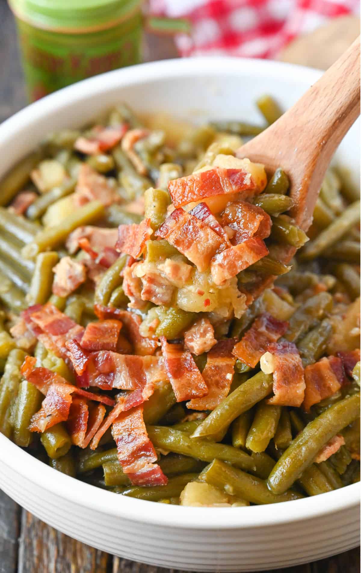 A wooden spoon scooping up some green beans.