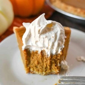 A slice of buttermilk pumpkin pie with a bute out of it.