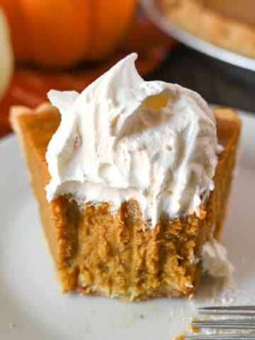 A slice of buttermilk pumpkin pie with a bute out of it.