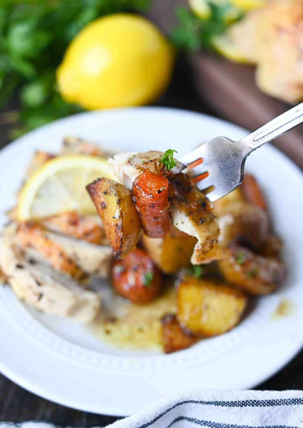 Lemon garlic roasted chicken with a potato and carrot bite on a fork.