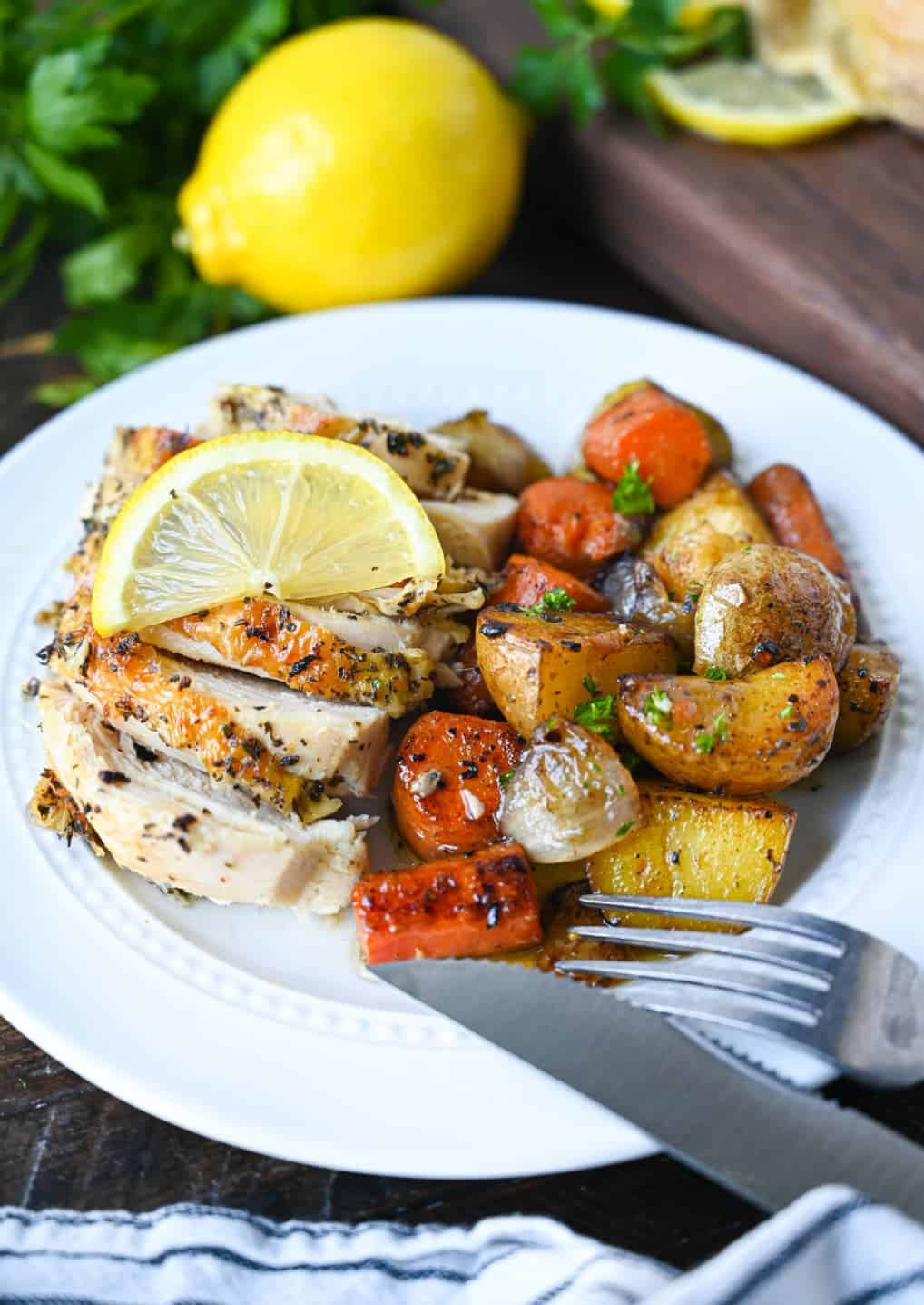 Sliced lemon galic chicken breast with a side of potatoes and carrots.