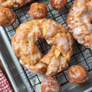 Apple cider donut with donut holes on a cooling rack.