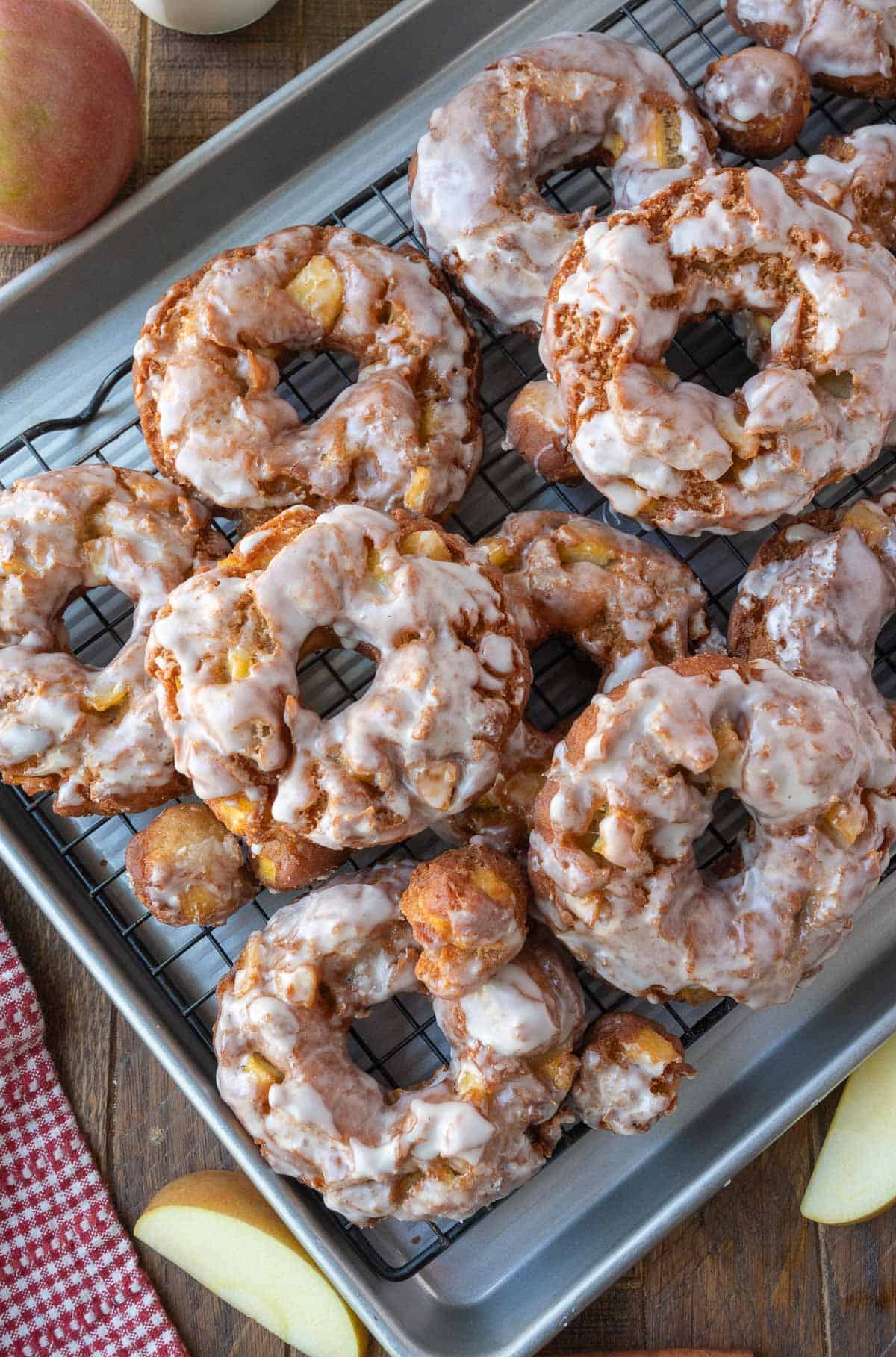 Apple cider donuts piled on a baking sheet.