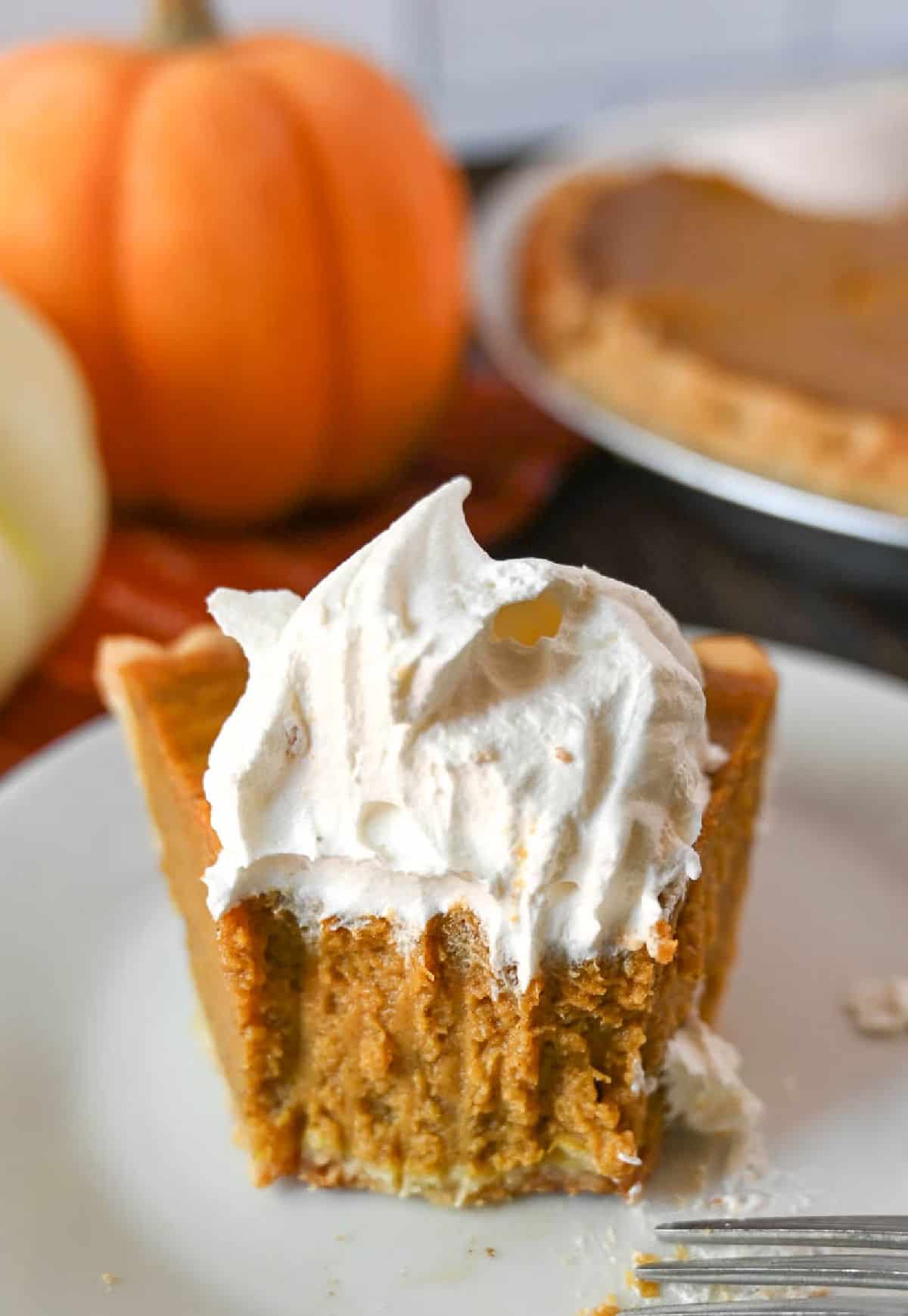 A slice of buttermilk pumpkin pie with a bute out of it.