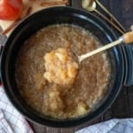 A serving spoon scooping up some applesauce from the slow cooker,