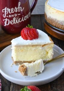 A slice of cheesecake on a white plate with a fork.