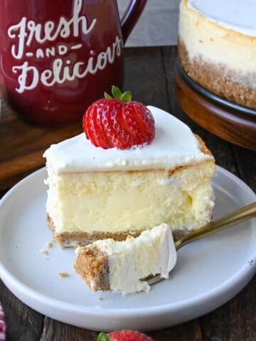 A slice of cheesecake on a white plate with a fork.