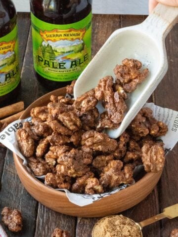 Spicy candied walnuts in a bowl with a scoop.