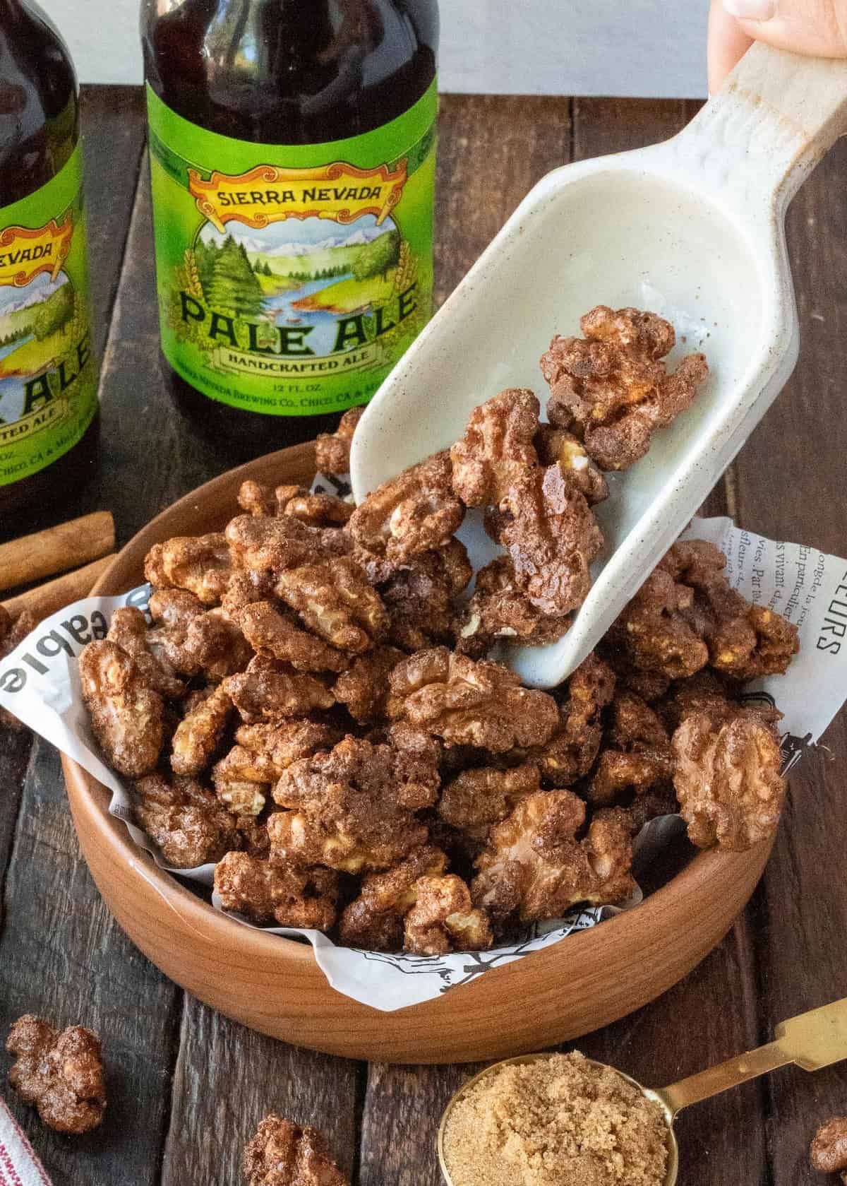 Spicy candied walnuts in a bowl with a scoop.