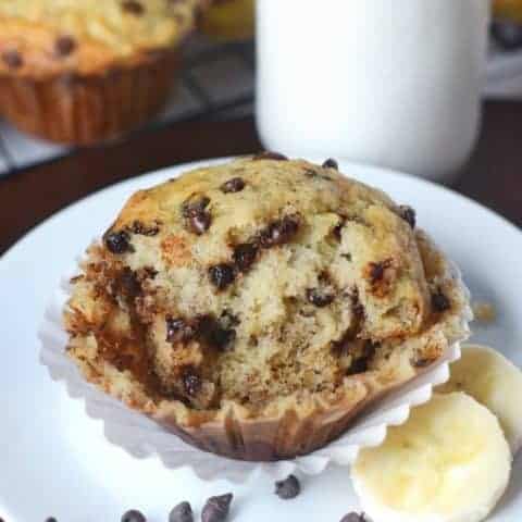 Chocolate chip banana muffin with slices of banana on a plate.
