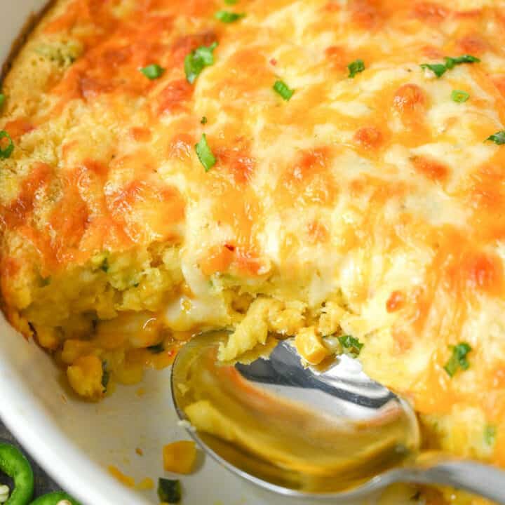 A baking dish with corn casserole in it and a serving missing.