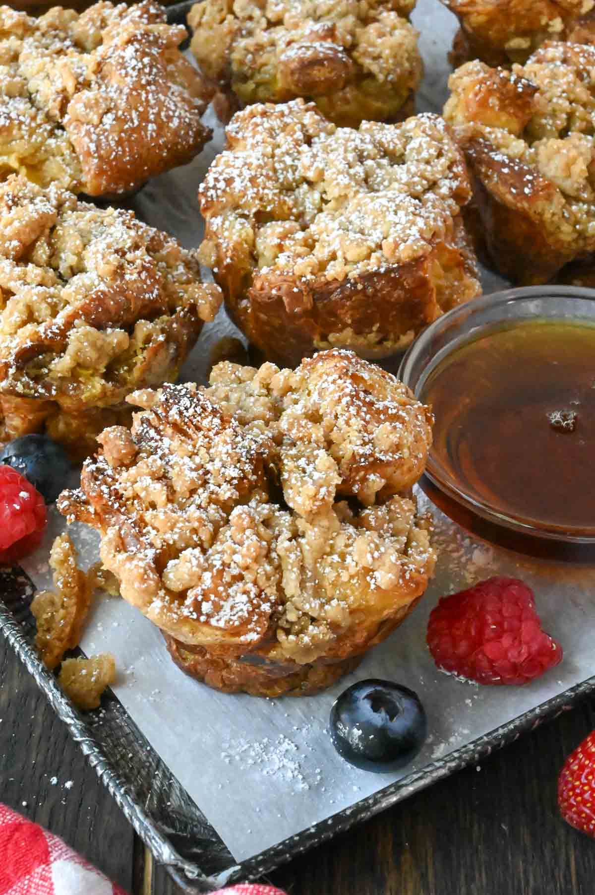 French toast muffins on a platter with a side of syrup and berries.