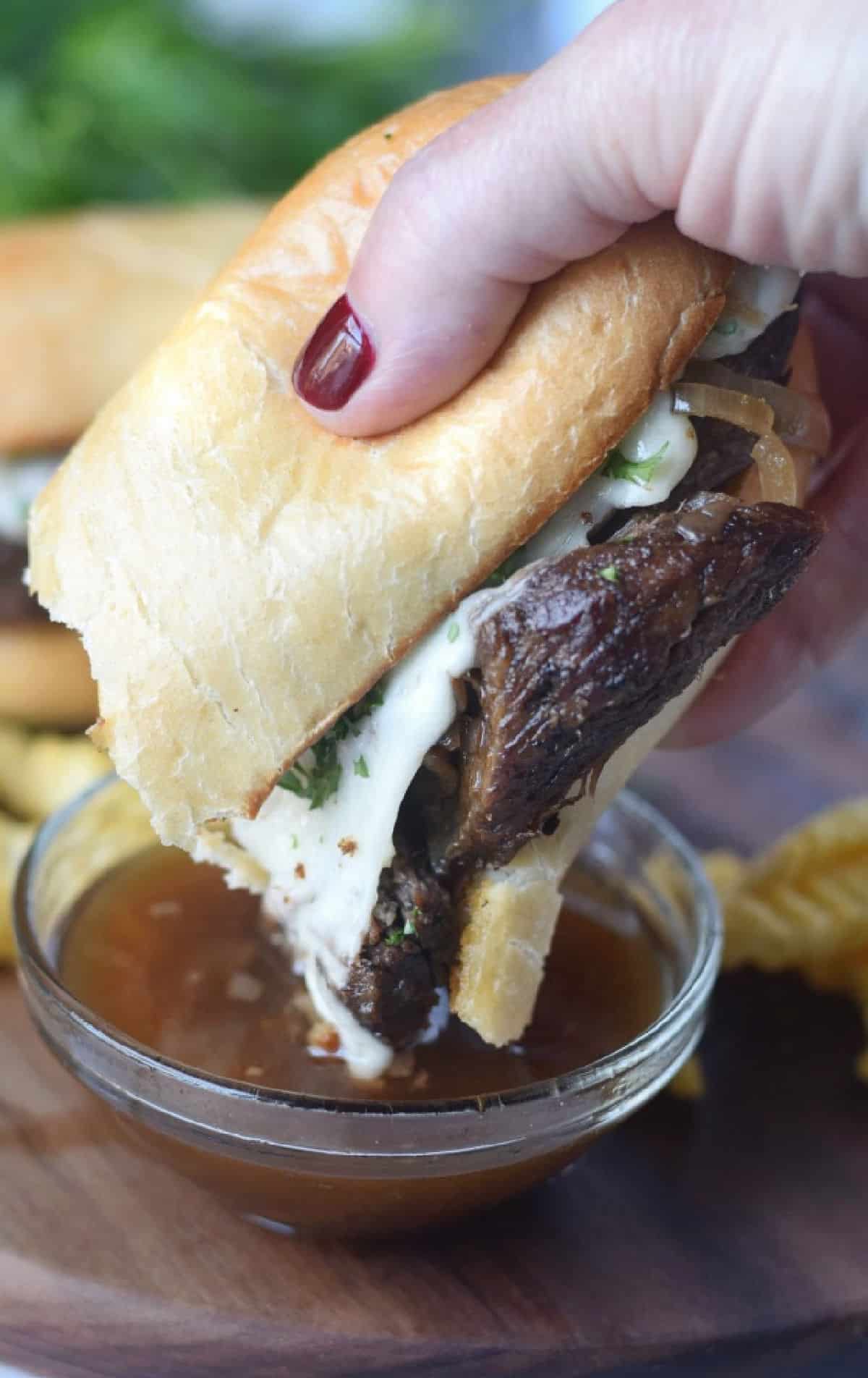 Sandwich being dipped in au jus.