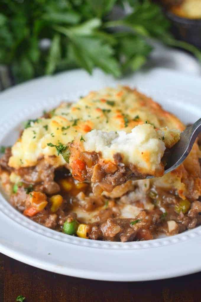 A plate of food with shepherd\'s pie and a fork.
