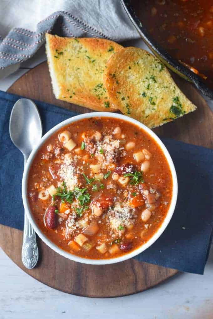 A bowl of food on a table, with Soup and Pasta.