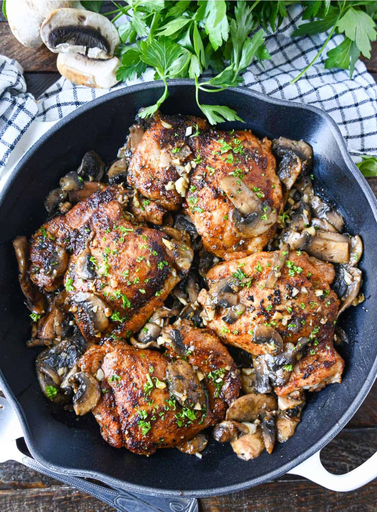 Garlic mushroom chicken thighs in a cast iron skillet.