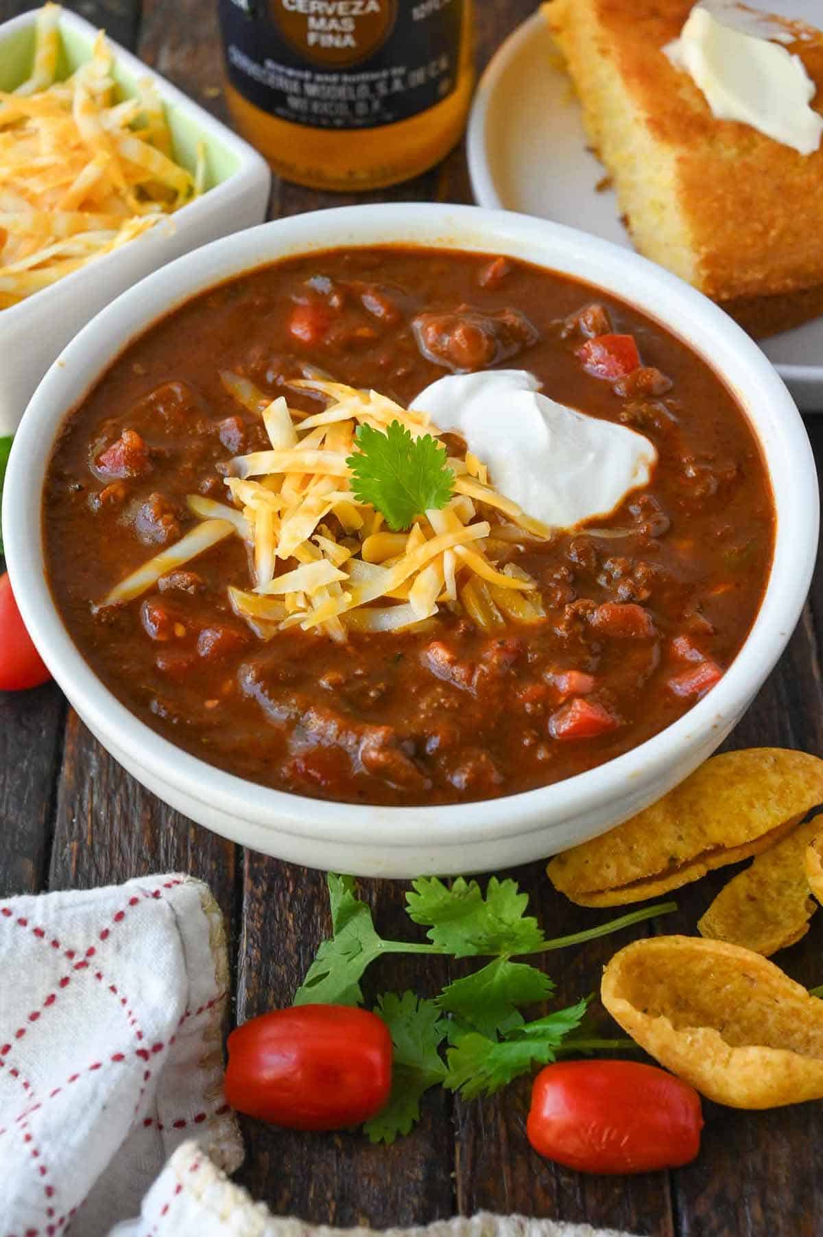 No bean chili in a white bowl with shredded cheese and sour cream on top.