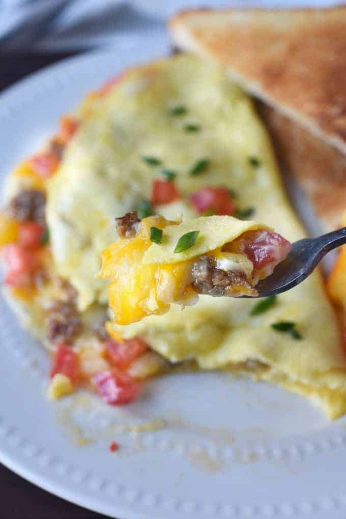A bite of omelet on a fork, with Cheese and Sausage