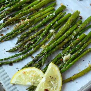 Roasted asparagus on a baking sheet with lemon slices.