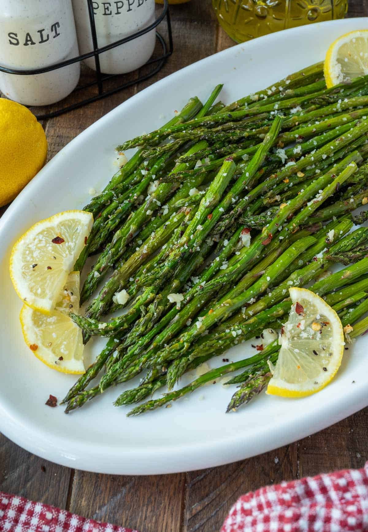 Roasted asparagus on a platter with lemon slices.