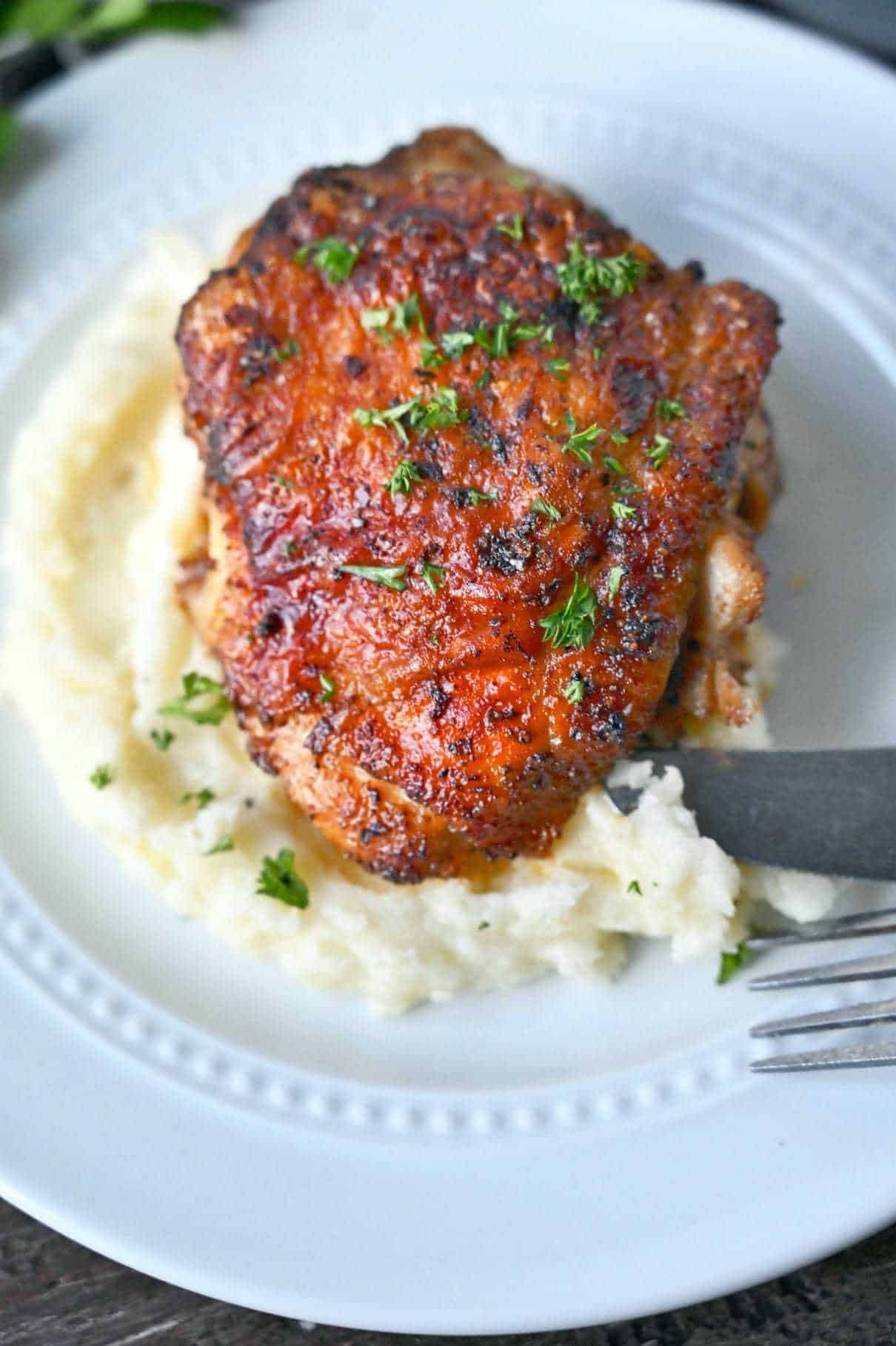 Crispy chicken thigh on a pile of mashed potatoes.